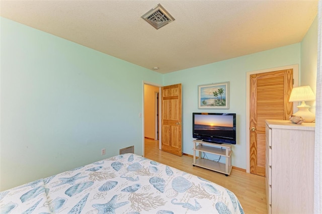 bedroom with a textured ceiling and light wood-type flooring