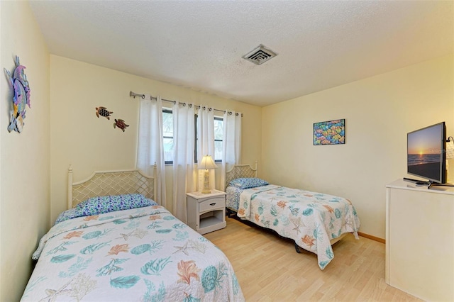 bedroom with light wood-type flooring and a textured ceiling