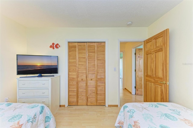 bedroom with a closet, a textured ceiling, and light hardwood / wood-style flooring