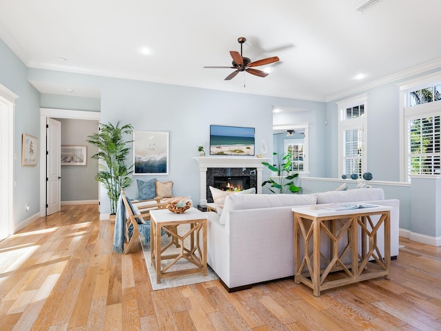 living room featuring a high end fireplace, light hardwood / wood-style flooring, and crown molding