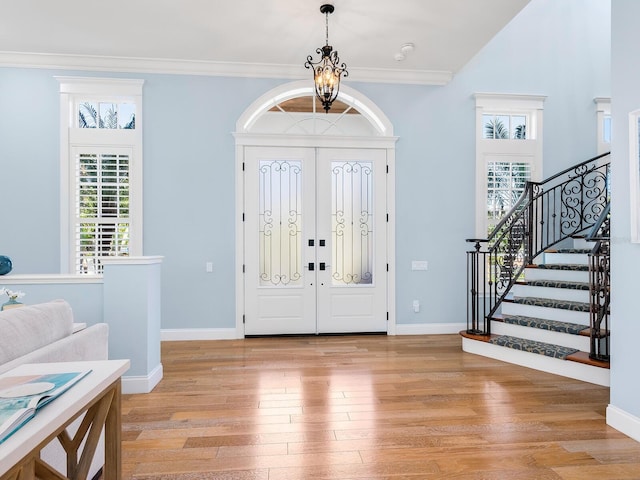 entrance foyer featuring an inviting chandelier, crown molding, and light hardwood / wood-style flooring