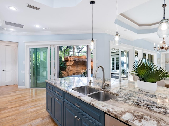 kitchen featuring light stone countertops, sink, a healthy amount of sunlight, and blue cabinets