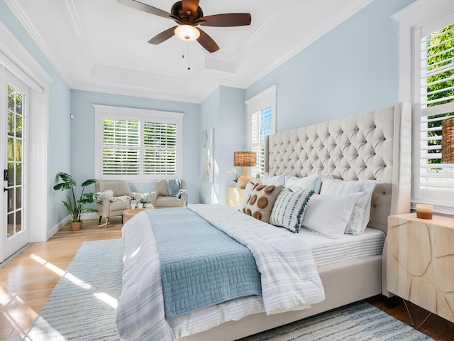 bedroom with a tray ceiling, multiple windows, ceiling fan, and wood-type flooring