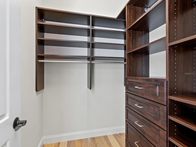 walk in closet with light hardwood / wood-style floors