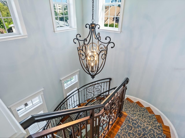 stairs featuring a notable chandelier, plenty of natural light, and hardwood / wood-style flooring