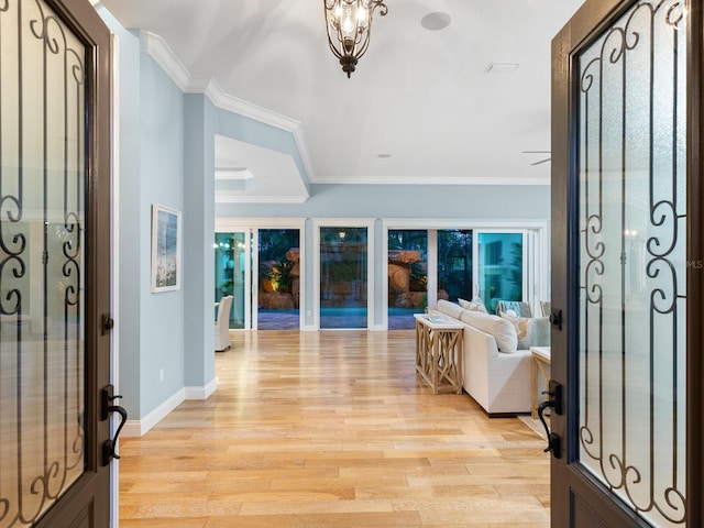 foyer entrance with a chandelier, light wood-type flooring, and ornamental molding