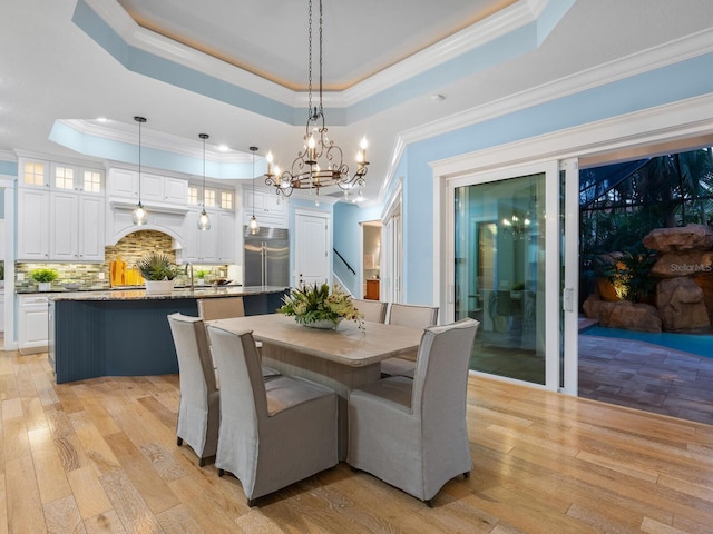 dining area featuring a tray ceiling, light hardwood / wood-style flooring, and ornamental molding