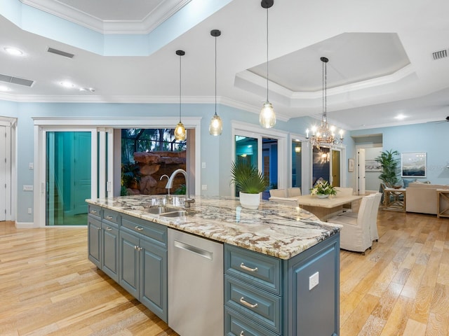 kitchen with stainless steel dishwasher, pendant lighting, a kitchen island with sink, and a tray ceiling