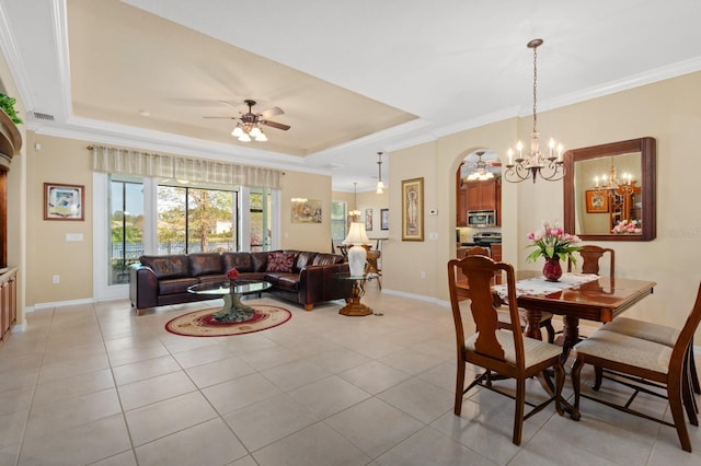 tiled dining area with ceiling fan with notable chandelier, a raised ceiling, and crown molding