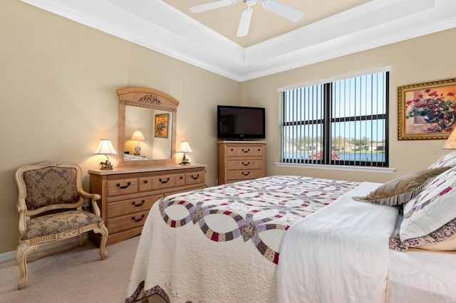 carpeted bedroom featuring a raised ceiling, ceiling fan, and crown molding