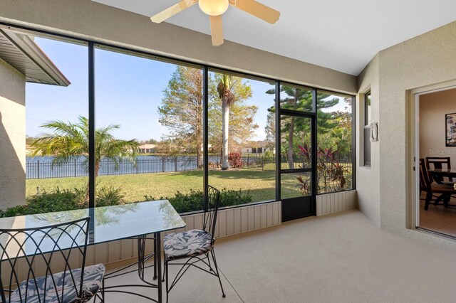 sunroom featuring ceiling fan, a healthy amount of sunlight, and a water view