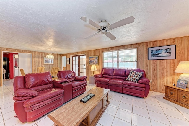 tiled living room featuring ceiling fan, wooden walls, and a textured ceiling