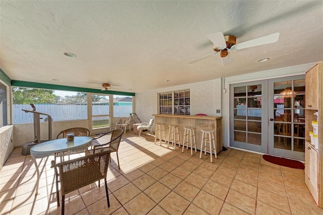 sunroom / solarium featuring french doors, a water view, and ceiling fan