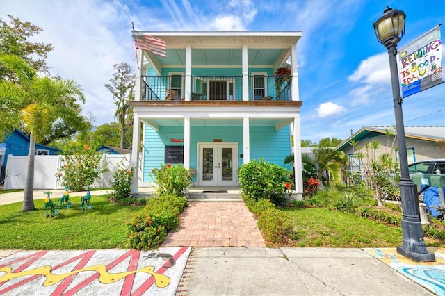 view of front of home featuring a front yard, french doors, and a balcony