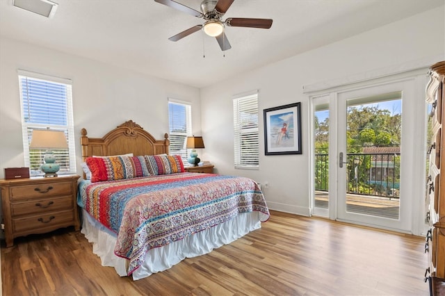 bedroom with ceiling fan, access to exterior, wood-type flooring, and multiple windows