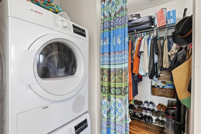 washroom with hardwood / wood-style floors and stacked washer / drying machine