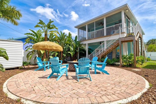 exterior space featuring a sunroom, ceiling fan, and a fire pit