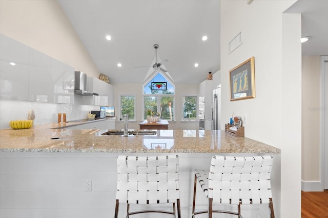 kitchen featuring kitchen peninsula, light stone countertops, sink, and lofted ceiling