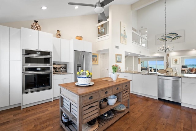 kitchen featuring white cabinets, high vaulted ceiling, decorative backsplash, and appliances with stainless steel finishes