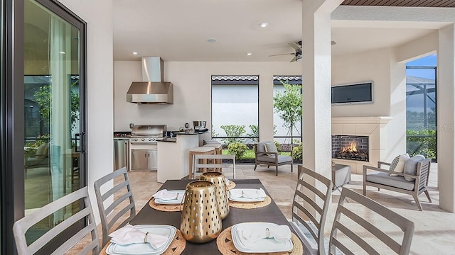 dining space with a tile fireplace and ceiling fan