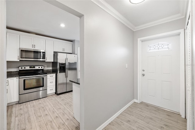 kitchen with ornamental molding, appliances with stainless steel finishes, white cabinets, and light wood-type flooring