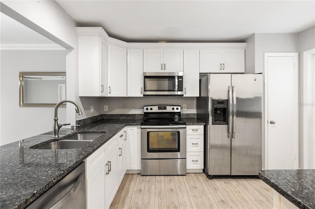 kitchen with stainless steel appliances, sink, dark stone counters, and white cabinets