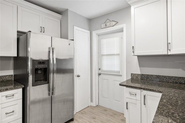 kitchen with stainless steel refrigerator with ice dispenser, white cabinetry, dark stone counters, and light wood-type flooring