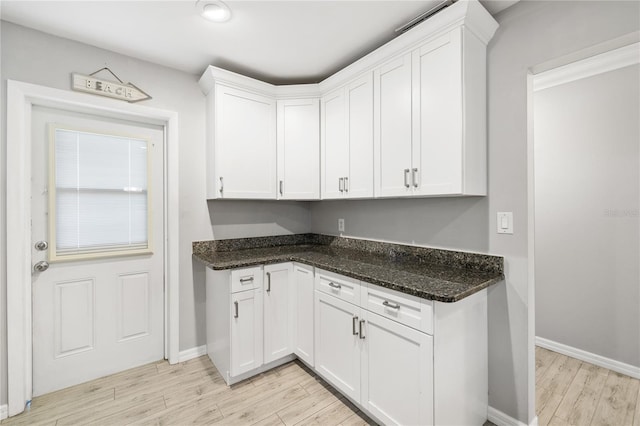 kitchen featuring dark stone countertops, white cabinets, and light wood-type flooring