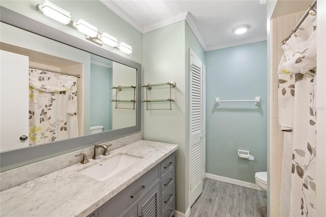 bathroom with vanity, crown molding, wood-type flooring, and toilet