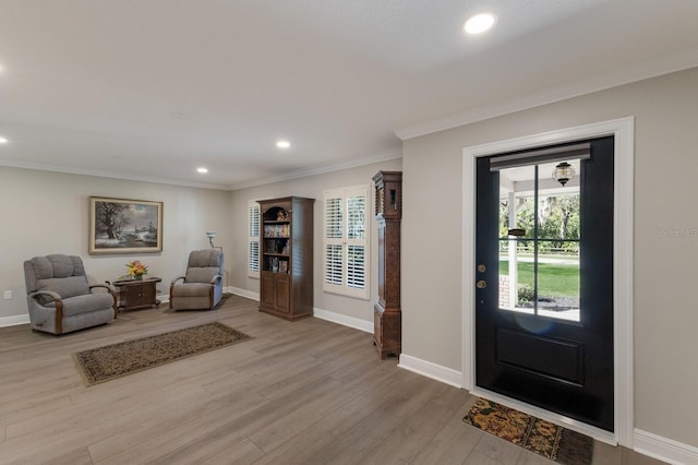 foyer with crown molding and light hardwood / wood-style flooring