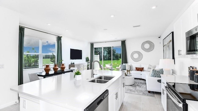 kitchen featuring white cabinets, a center island with sink, stainless steel appliances, and sink