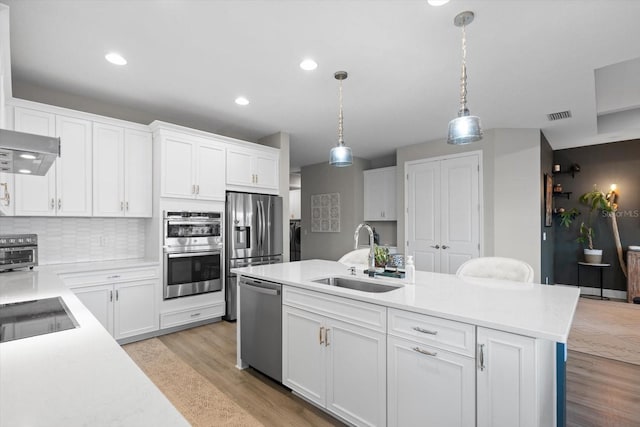 kitchen with sink, white cabinets, pendant lighting, and appliances with stainless steel finishes