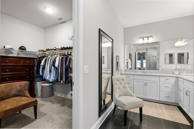 bathroom with tile patterned flooring, vanity, a textured ceiling, and walk in shower