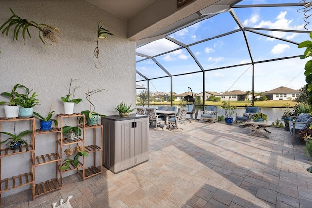 view of patio with a water view and glass enclosure