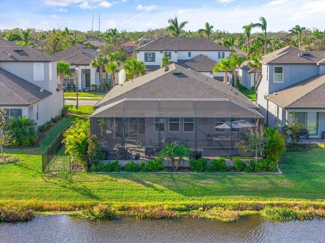 rear view of house featuring a lanai, a lawn, and a water view