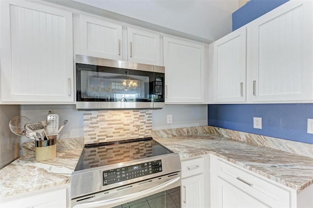 kitchen with tile patterned flooring, appliances with stainless steel finishes, white cabinetry, and light stone counters