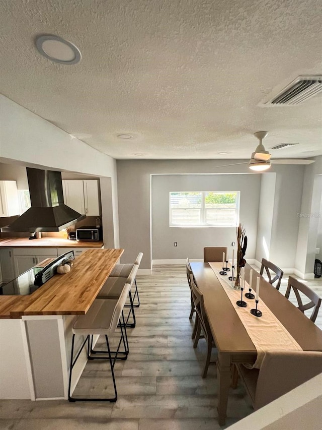 dining space featuring a textured ceiling, light wood-type flooring, and ceiling fan