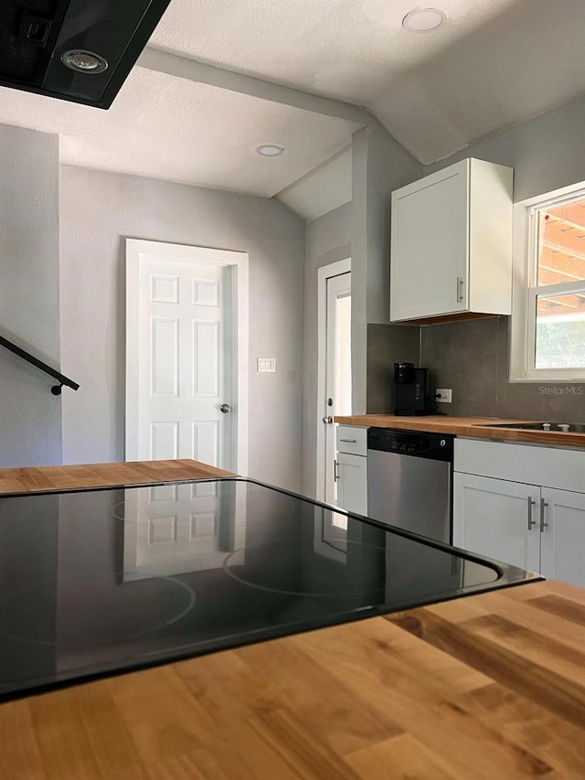 kitchen featuring stainless steel dishwasher, white cabinets, and wooden counters