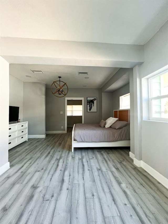 unfurnished bedroom featuring multiple windows, light hardwood / wood-style floors, and an inviting chandelier