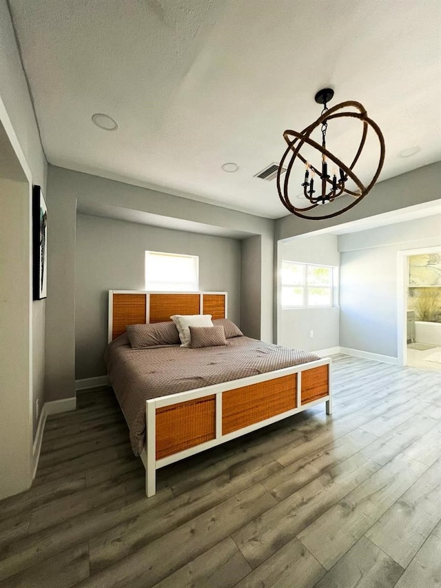 bedroom featuring a notable chandelier, dark hardwood / wood-style flooring, and ensuite bath