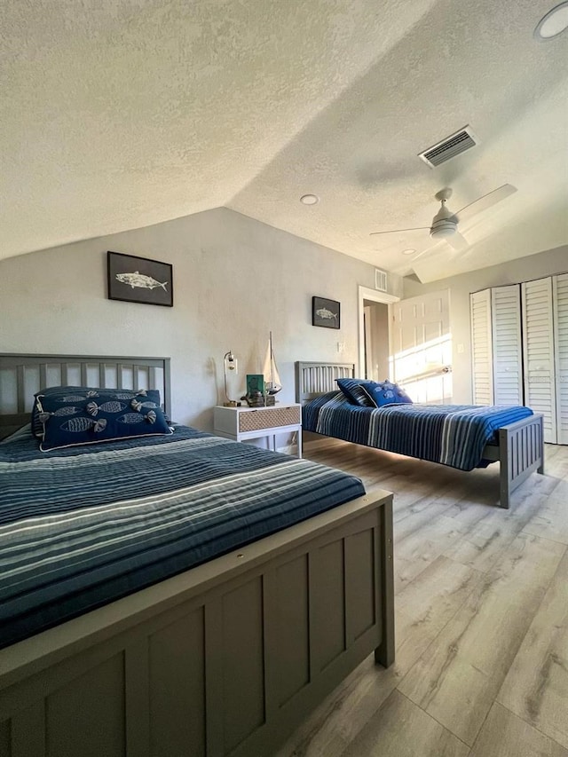 bedroom with a textured ceiling, ceiling fan, and vaulted ceiling