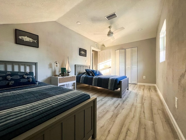 bedroom with light wood-type flooring, a textured ceiling, ceiling fan, a closet, and lofted ceiling