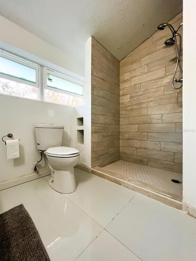 bathroom featuring tile patterned flooring, a tile shower, vaulted ceiling, and toilet