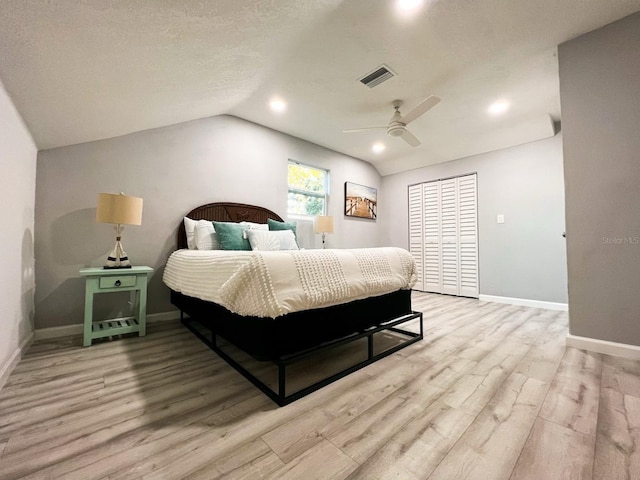 bedroom with a textured ceiling, vaulted ceiling, ceiling fan, hardwood / wood-style floors, and a closet