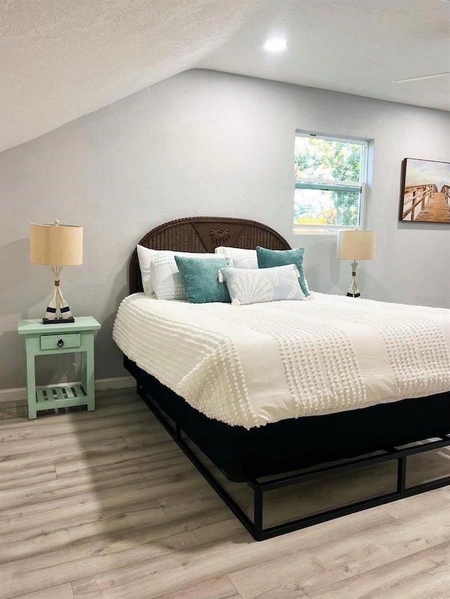 bedroom featuring a textured ceiling, wood-type flooring, and vaulted ceiling