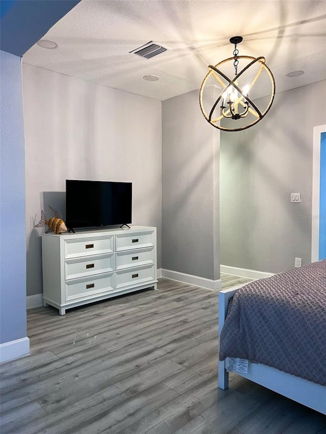 bedroom with hardwood / wood-style floors, a textured ceiling, and a chandelier