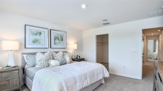 bedroom with a spacious closet, a closet, and light carpet