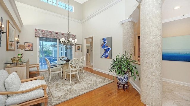 dining area with a towering ceiling, an inviting chandelier, ornate columns, and plenty of natural light