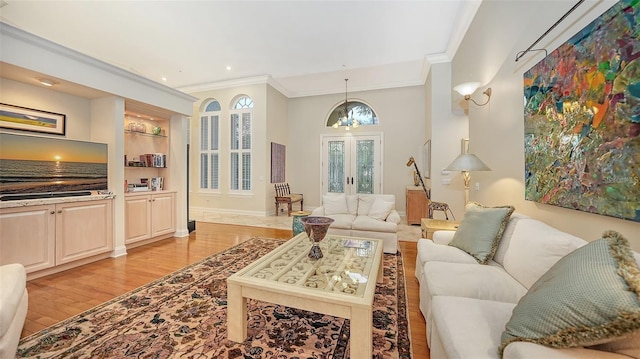 living room with built in shelves, french doors, light hardwood / wood-style flooring, a chandelier, and ornamental molding