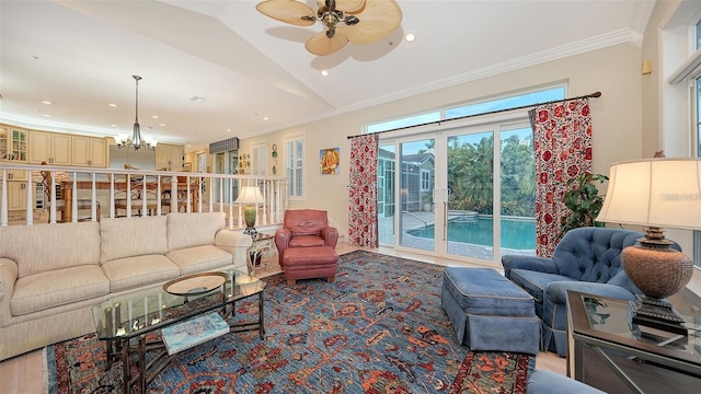 living room featuring ceiling fan with notable chandelier, ornamental molding, and vaulted ceiling